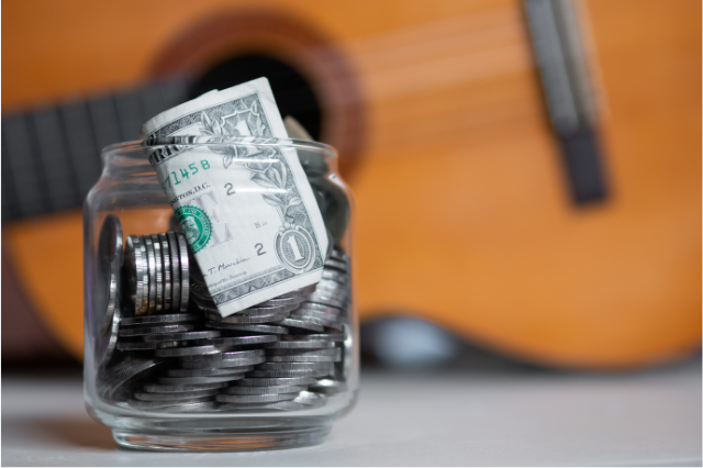 money or tips in jar with guitar